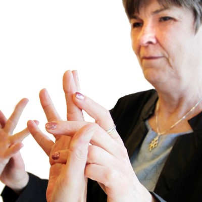 Portræt af Dorte Eriksen der står med en blindestok i hånden: Mennesker, der har mistet både hele høre- og hele synssansen, er henvist til at kommunikere via taktilt tegnsprog, hvor man føler tegnene med hånden