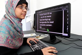 Ung døvblind kvinde arbejder ved PC med stor skrift